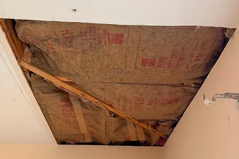 Wet stained fiberglass insulation exposed through an opened ceiling after a roof leak
